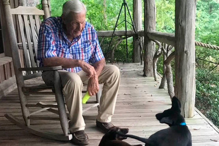 Coach Pat Dye on front porch with his two black labs.
